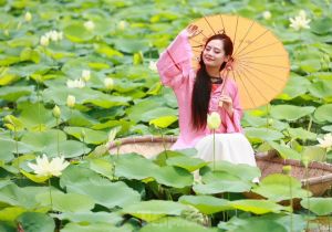 Vietnam's young people wearing Ao Dai take photos next to white lotus flowers